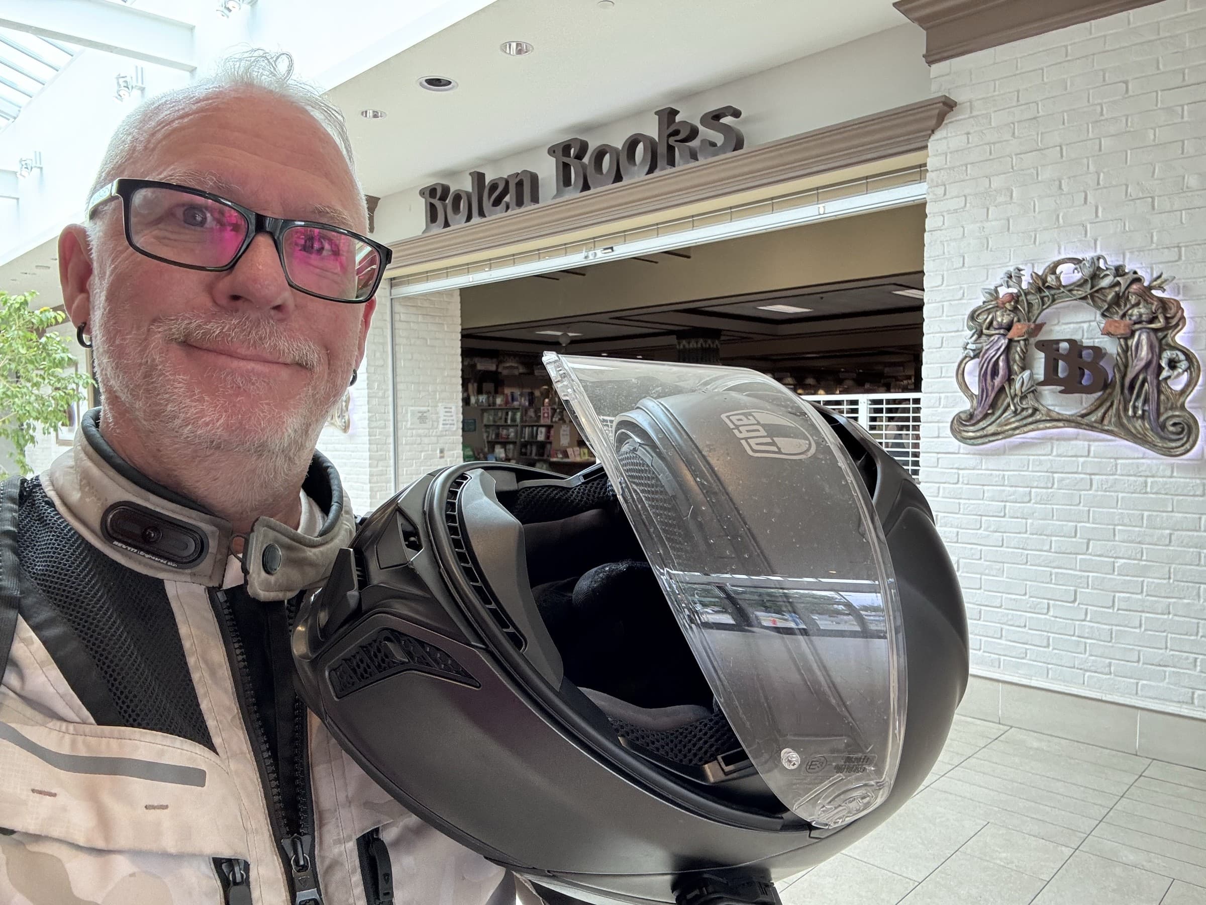 Michael Dargie holding a motorcycle helmet outside Bolen Books on the BrandJitsu® BC Book Tour