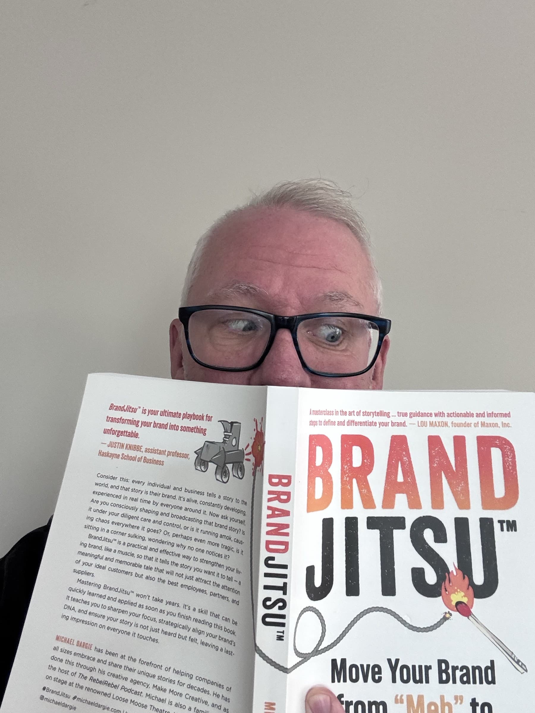 Michael Dargie holding the BrandJitsu® book up to his face, reading his own work