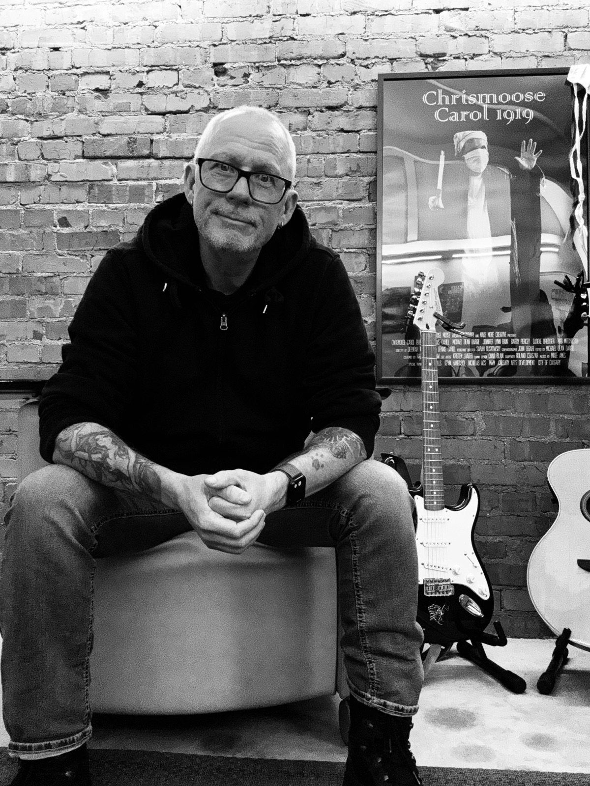 Michael Dargie in the studio, guitars and a Chrismoose Carol 1919 theatre poster behind him